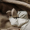 Baby draagt beige wollen babyslofjes met sluiting aan de voorzijde
